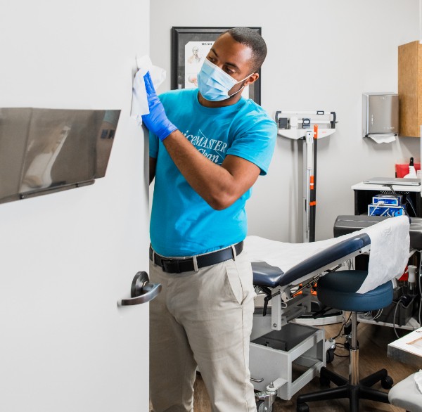 A ServiceMaster expert sanitizing a door in a doctor’s office during janitorial services